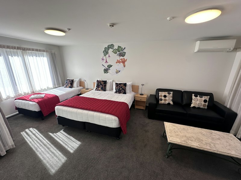 Deluxe Studio with king and single beds, sofa and coffee table
