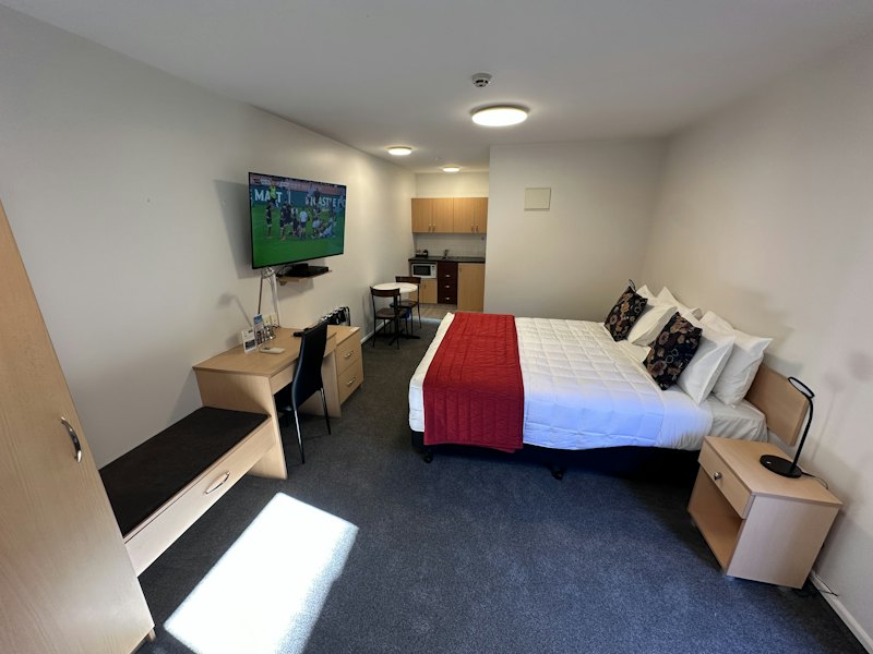 Studio room with bed, TV, desk and kitchenette